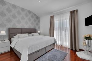 a white bedroom with a large bed and a window at Apartment Star in Makarska