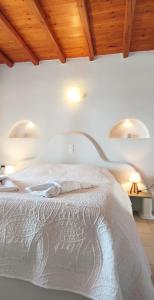 a bedroom with a white bed with wooden ceilings at Orionides in Tinos