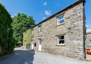 an old stone house with a driveway at East Cottage in Thwaite