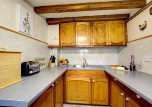 una cocina con armarios de madera y fregadero en East Cottage, en Thwaite