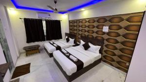 um quarto com três camas num quarto com luzes azuis em Hotel Plaza Rooms - Prabhadevi Dadar em Mumbai