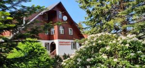 a red and white building with trees in the foreground at Apartments in Villa Barbara in Świeradów-Zdrój