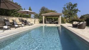 een zwembad met stoelen en een parasol bij Villa Mediterranean Retreat in Tinjan