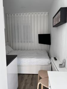 um pequeno quarto branco com uma cama e uma televisão em CASAS DONA EMILIA em Vieira de Leiria
