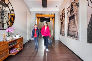 two women walking down a hallway with art on the walls at Hotel Volksschule in Hamburg