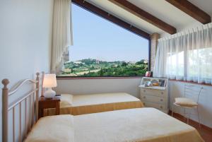 um quarto com 2 camas e uma grande janela em Agriturismo Raccianello em San Gimignano