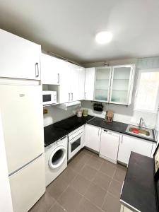 a kitchen with white cabinets and a washer and dryer at Cómodo y acogedor apartamento in Madrid