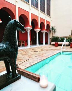 une statue d'un chien à côté d'une piscine dans l'établissement Hospederia Baños Arabes De Cordoba, à Cordoue