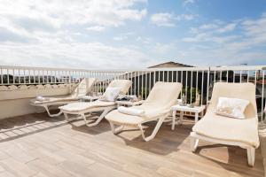 - un ensemble de chaises blanches assises sur un balcon dans l'établissement Cav Approdo, à Castiglione della Pescaia