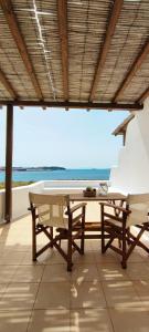 a table and benches in a room with a view of the ocean at Orionides in Tinos