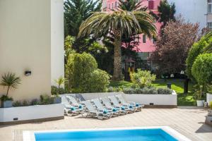 a patio with lounge chairs and a swimming pool at Hotel Londres Estoril / Cascais in Estoril