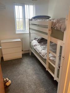 Cette chambre comprend 2 lits superposés et une fenêtre. dans l'établissement Lovely 2nd floor 2 bed flat sleeps 4, à Doncaster