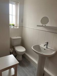 La salle de bains blanche est pourvue de toilettes et d'un lavabo. dans l'établissement Lovely 2nd floor 2 bed flat sleeps 4, à Doncaster