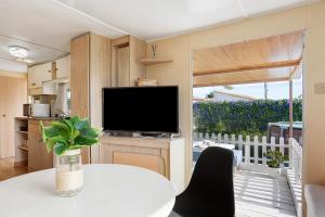 sala de estar con TV y mesa blanca con mesa de mesa en Villa Triana, en Chiclana de la Frontera