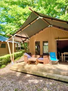 une tente avec une table et des chaises sur une terrasse en bois dans l'établissement Camping de la Forêt Seasonova, à Sillé-le-Guillaume