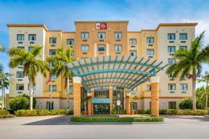 a hotel with a large building with palm trees at Best Western Plus Miami Executive Airport Hotel and Suites in Kendall