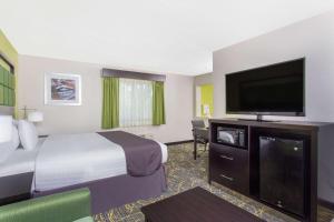 a hotel room with a bed and a flat screen tv at AmericInn by Wyndham Delafield in Delafield