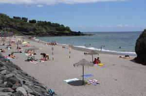 a group of people on a beach with umbrellas at Sunrise House- 4 bedroom house with amazing sunrise over the sea 8 guests in Vila Franca do Campo