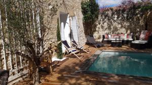 a swimming pool with two lounge chairs next to a wall at La Demeure du Pressoir in Cuxac-dʼAude