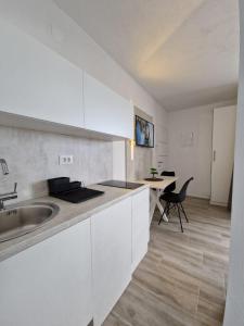 eine weiße Küche mit einem Waschbecken und einem Tisch in der Unterkunft Elegance Dream Apartment in Neum