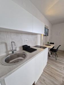 eine weiße Küche mit einem Waschbecken und einem Tisch in der Unterkunft Elegance Dream Apartment in Neum