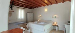 niewielka sypialnia z białym łóżkiem i stołem w obiekcie Orionides w mieście Tinos