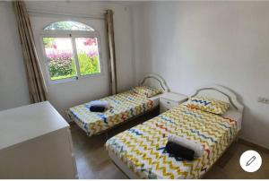 two beds in a small room with a window at SUPERBE T3 RIVIERA DEL SOL Plage et commerces 4mn in Mijas +18 photos
