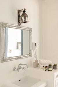 a white bathroom with a mirror and a sink at Akrolithos Villas in Kouvaláta +35 photos