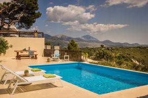 a villa with a swimming pool with mountains in the background at Akrolithos Villas in Kouvaláta