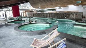 a large swimming pool with two chairs in a building at Cottage des Pléiades - Station de ski accessible à pieds in Les Angles