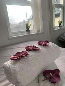 a white bed with purple flowers on top of it at AK Serviced Apartments - Exclusive Two-Bedroom Apartment in Cardiff