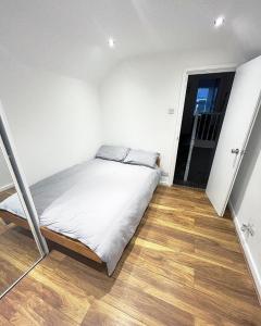 um pequeno quarto com uma cama e piso em madeira em AK Serviced Apartments - Exclusive Two-Bedroom Apartment em Cardiff