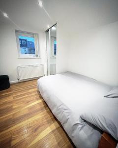 um quarto com uma cama branca e uma janela em AK Serviced Apartments - Exclusive Two-Bedroom Apartment em Cardiff