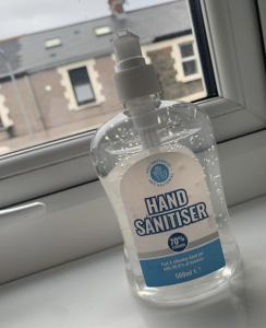 uma garrafa de desinfectante para as mãos sentada à frente de uma janela em AK Serviced Apartments - Exclusive Two-Bedroom Apartment em Cardiff