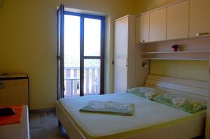 a bedroom with a bed and a window with a balcony at Apartments and Rooms Villa Mir in Zaton