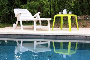 - deux chaises et une table à côté de la piscine dans l'établissement La Cerisaie, maison spacieuse en Lubéron, à Saint-Martin-de-Castillon