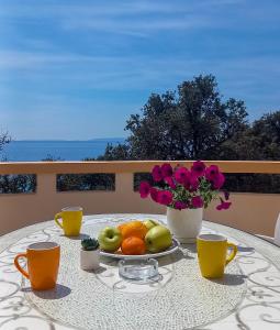 a table with a plate of fruit and two cups at Apartments MULOBEDANJ in Lun