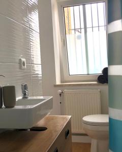 ein Bad mit einem Waschbecken, einem WC und einem Fenster in der Unterkunft Gemütliches Appartement "Nina" in Halle in Rusches Hof