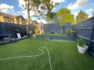 a backyard with a green lawn with a hose at 5 bedroom House SE6 in Hither Green