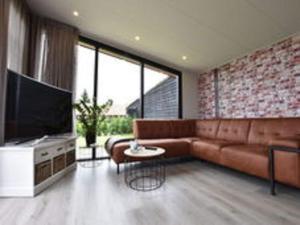 sala de estar con sofá y TV en Serene chalet in Haulerwijk with enclosed garden and views, en Haulerwijk