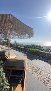 a beach with chairs and an umbrella and the ocean at Phaos Santorini Suites in Imerovigli