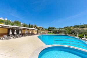 a large swimming pool with chairs and umbrellas at Vale da Ribeira - Casa Serenidade in Mexilhoeira Grande