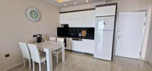 a white kitchen with a table and a refrigerator at Konak Tower Seaside in Alanya