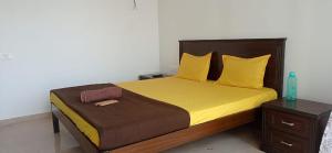 1 dormitorio con 1 cama con sábanas amarillas y cabecero de madera en P N A Apartments - Manpada, en Thane