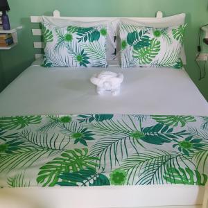 a bed with a green and white bedspread with a flower on it at Isla Vista Apartment Canouan in Canouan