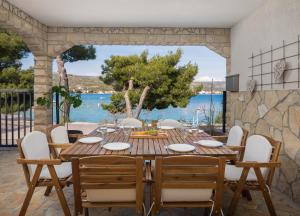 a wooden table and chairs with a table and a view of the ocean at Estella Villa in Rogoznica