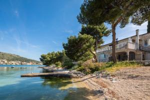 a house on the shore of a lake with trees at Estella Villa in Rogoznica