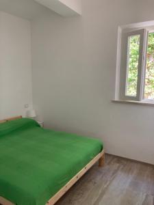 een slaapkamer met een groen bed in een kamer met een raam bij Villetta cod. 454 Taunus Vacanze in Numana