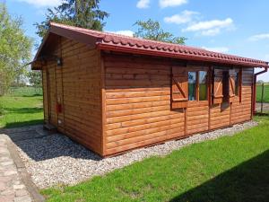 eine kleine Holzhütte mit rotem Dach in der Unterkunft Domek 2 w Rancho Żnin in Żnin