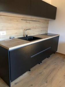 a kitchen with a black sink and a wooden floor at appartamento Passo del Tonale sulle piste in Passo del Tonale
